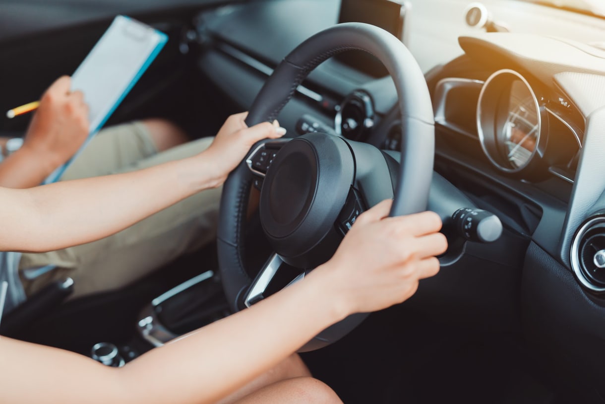 Mani sul volante di un'auto accanto a un blocco per appunti