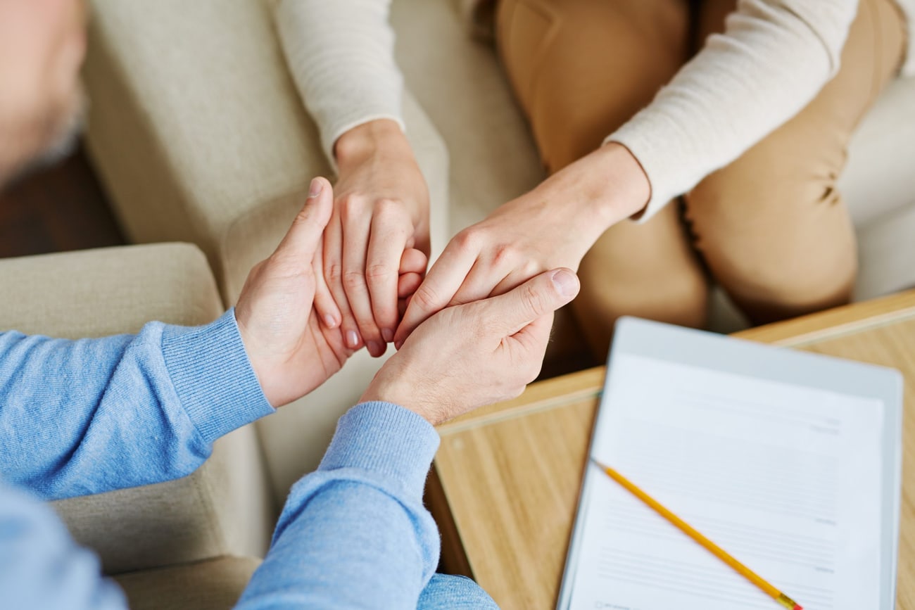 Mani che si stringono in segno di sostegno, attorno a un tavolo di lavoro